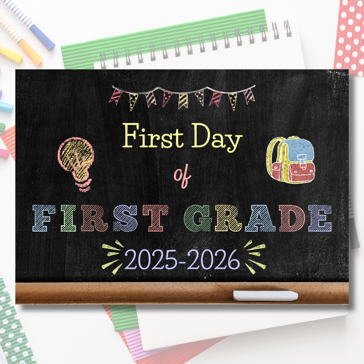 Chalkboard sign for the 'First Day of First Grade 2025-2026' with school supplies in the background.